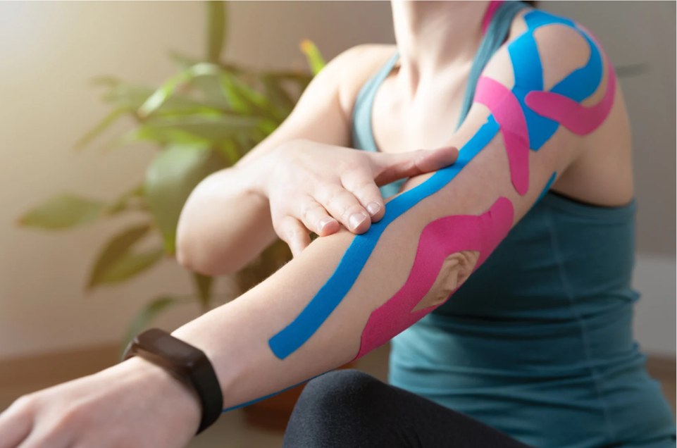 Woman with kinesiology tape applied to arm and shoulder for muscle support during Kinesio Taping therapy at Balance Naturopathic & Acupuncture in Mooresville, NC.